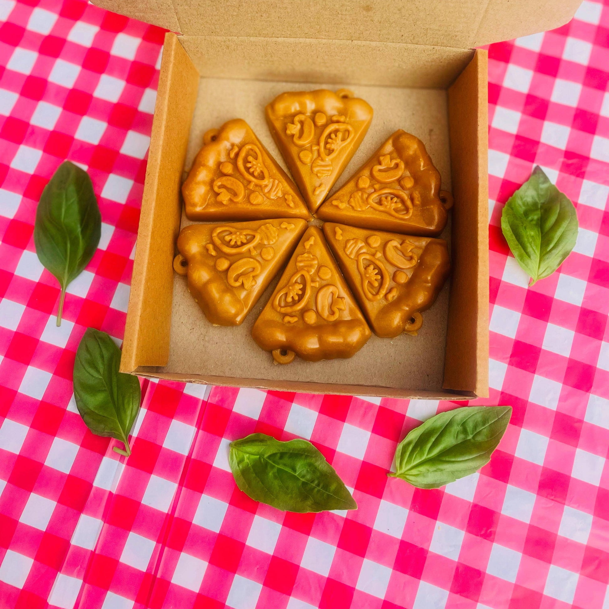 Box of dog treats with pawfect luna co logo on a pink and white checkered tablecloth.